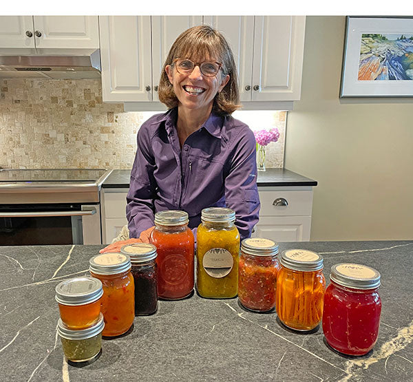 Woman behind counter that is displaying jars filled with different vegetables