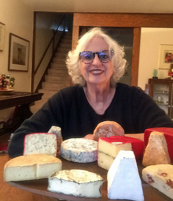 A woman smiling with cheese in front of her.