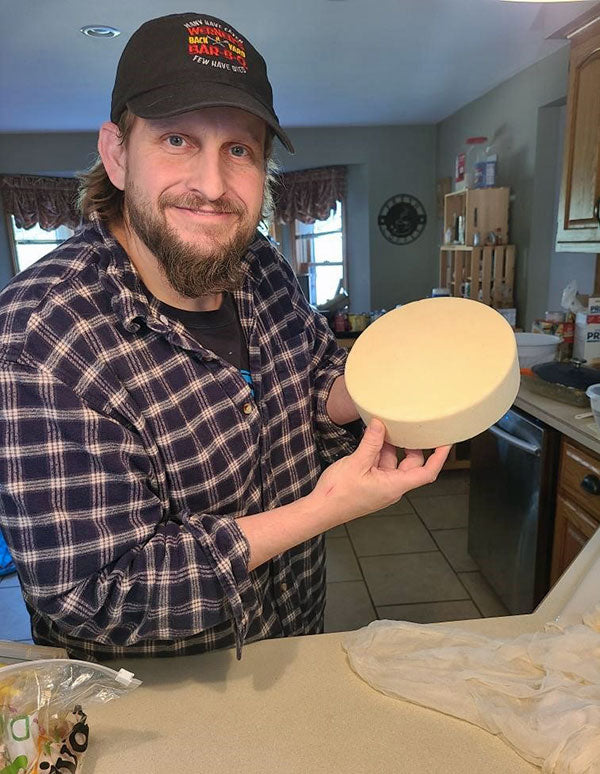 A man holding a wheel of cheese.