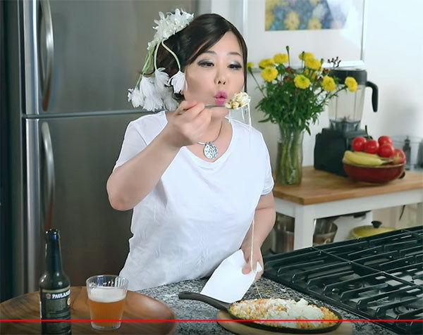 Woman blowing on hot cheese taken from pan