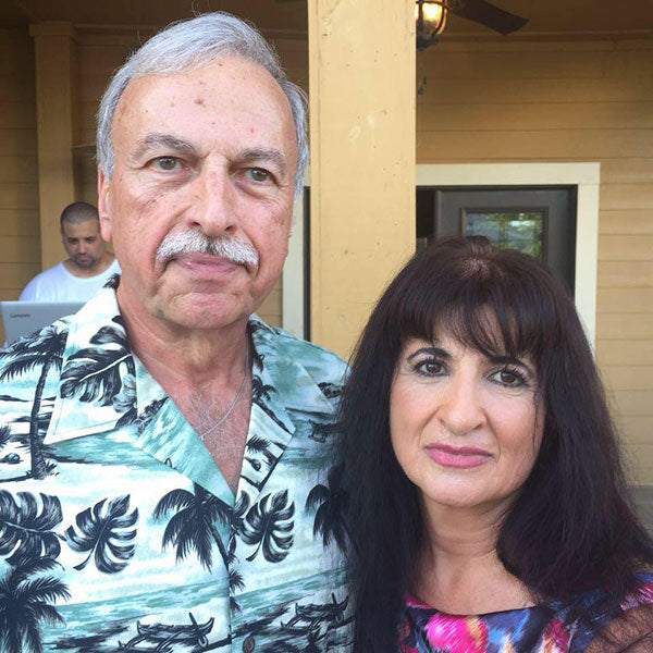 A couple smiling in front of a house